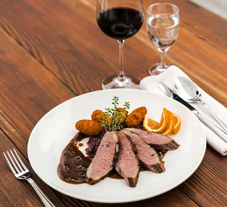 Tranchierte Entenbrust mit Kroketten und Rotkraut, dazu Rotwein