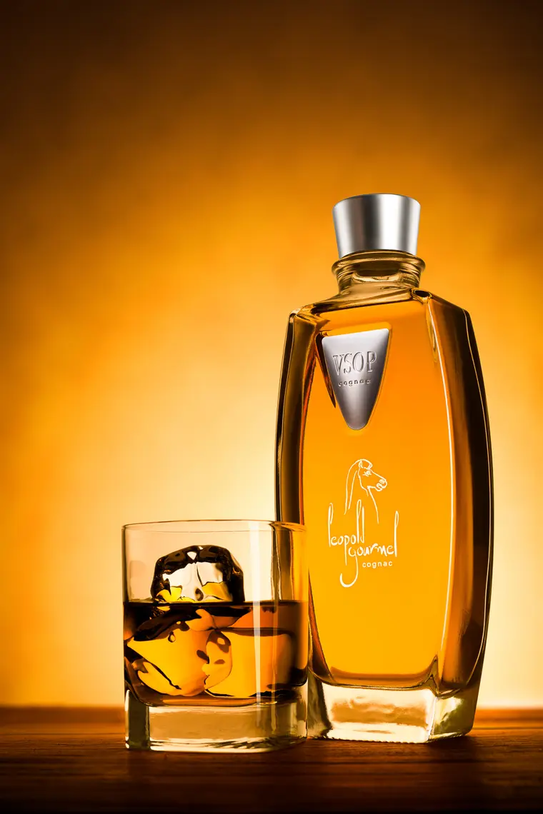 Cognacflasche und gefülltes Glas vor warmem Lichtverlauf