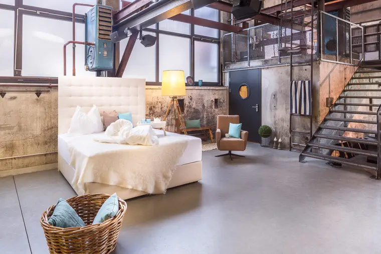 Schlafzimmer im Loftstil mit Bett und Sitzsessel