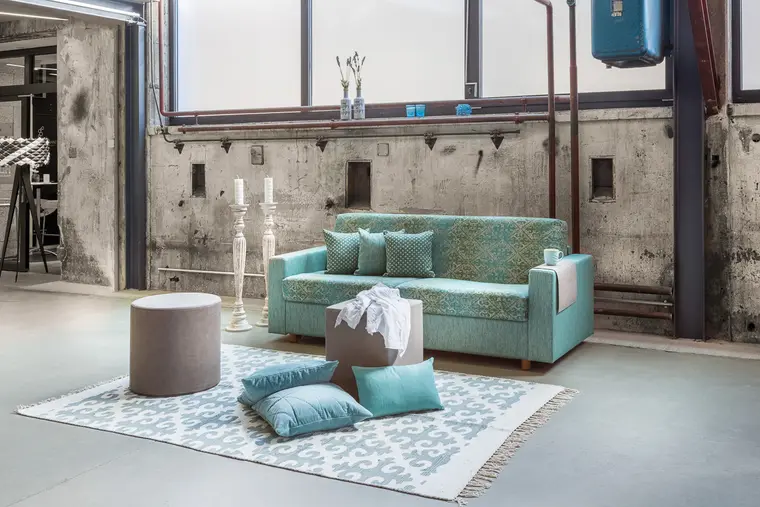 Wohnraum im Loftstil mit türkisfarbenem Sofa